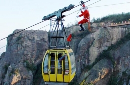 “圣诞老人”爬高空索道为游客送礼