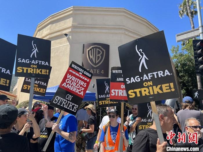 当地时间7月14日上午，华纳兄弟、迪士尼等美国影视娱乐产业巨头总部门前，有成百上千的人高举“罢工”标语牌游行示威。由于未能与美国电影和电视制片人联盟(AMPTP)就新合同达成协议，拥有约16万名会员的好莱坞三大工会之一美国影视演员协会(SAG-AFTRA)发起罢工，于14日起在洛杉矶和纽约的十余家制片公司外示威游行。 <a target='_blank' href='/'>中新社</a>记者 张朔 摄